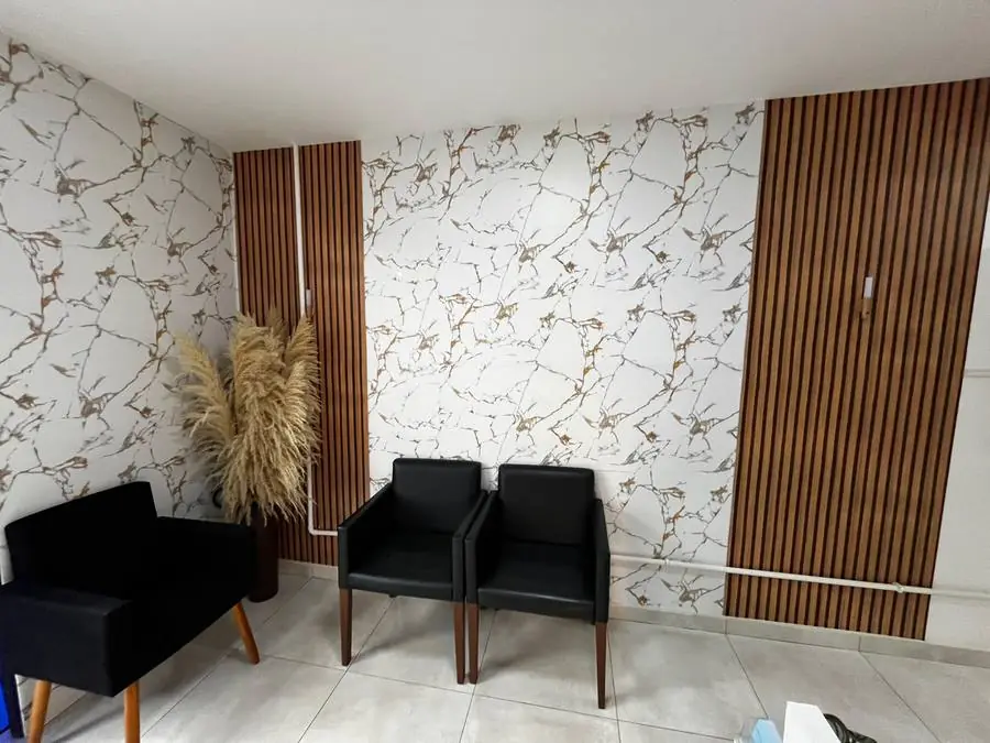 Recepção da Odontologia Monteiro, com poltronas e parede em mármore